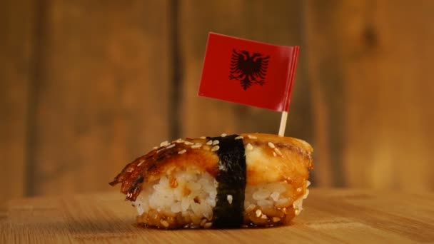 Sushi with fish, rice, seaweed and small flag of Albania on top rotate on a wooden turntable. — Stock Video