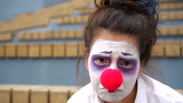 Сумний клоун з білим обличчям і червоним носом дивиться на камеру — стокове відео