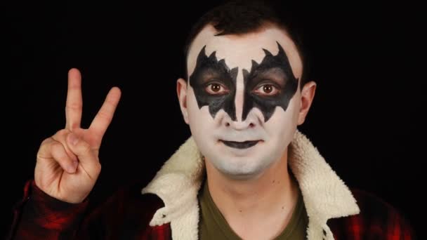 Muž v démon make-up ukazuje vítězství gesto na černém pozadí — Stock video