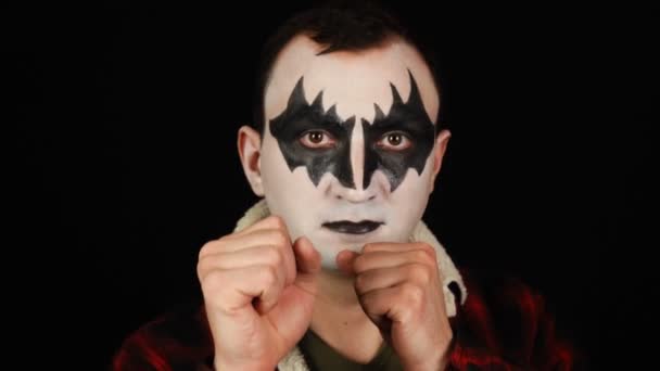 Aggressiv man i demon makeup stående i en boxning pose på svart bakgrund — Stockvideo