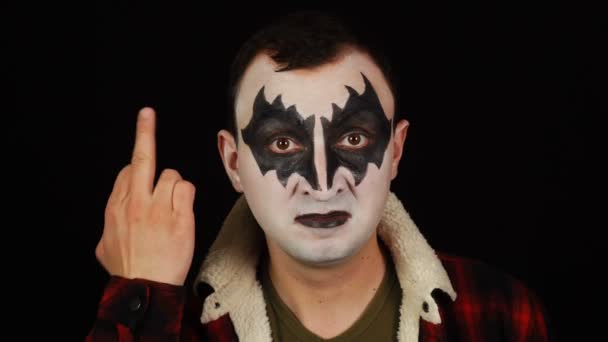 Man in demon makeup making a fuck gesture on black background — Stock Video