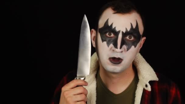 Człowiek w strasznym demonicznym makijażu z nożem na czarnym tle. — Wideo stockowe