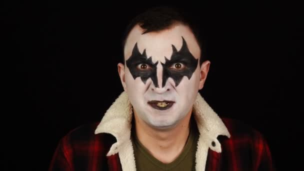Nieszczęśliwy mężczyzna w demonicznym makijażu pokazuje wściekłe negatywne emocje na czarnym tle — Wideo stockowe