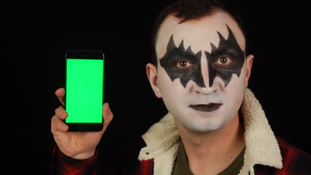 Hombre en maquillaje demonio miedo mostrando teléfono inteligente con pantalla verde — Vídeos de Stock