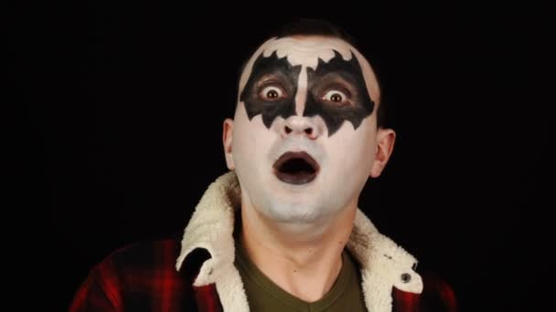 Емоційно шрамована людина в демонічному макіяжі шокована на чорному тлі — стокове відео