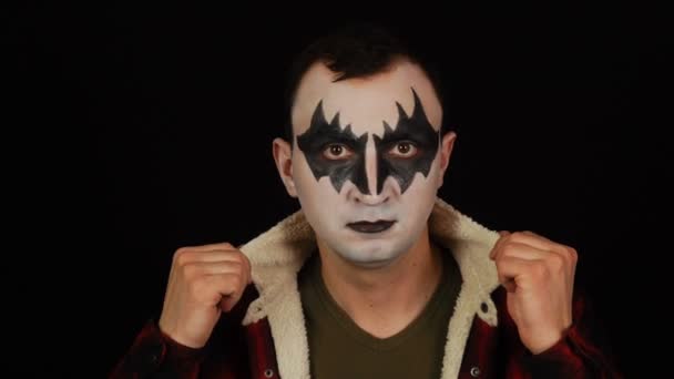Чоловік в демоні макіяж позує на камеру на чорному тлі — стокове відео