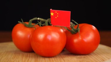 Adam Çin bayrağıyla dekoratif kürdanı domates demetine yerleştiriyor..
