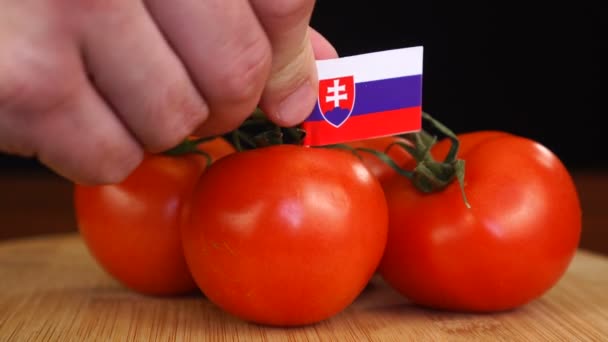 Man placing decorative toothpick with flag of Slovakia into bunch of tomatoes. — Stock Video