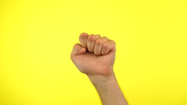 在黄色背景下举起拳头进行政治抗议，以展示他的权力。握紧拳头. — 图库视频影像