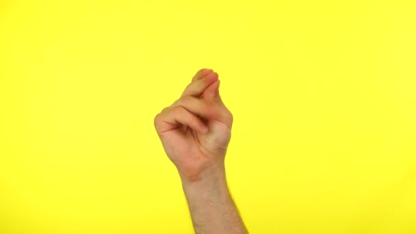 Mans hand knipt zijn vinger doet de hand gebaar geïsoleerd op een gele studio achtergrond — Stockvideo