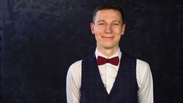Stylish cherefull young man in a vest with a bow-tie winking and looking at camera. — Stock Video