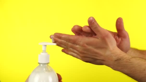 Το αντρικό χέρι πλένεται με σαπουνόφουσκες. Καθαρισμός χεριών με λευκές σαπουνόφουσκες σε κίτρινο φόντο — Αρχείο Βίντεο
