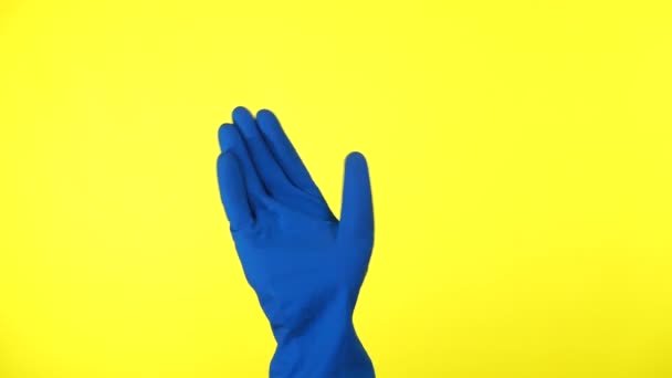 La mano masculina en guante azul le da la bienvenida sobre un fondo amarillo. — Vídeo de stock