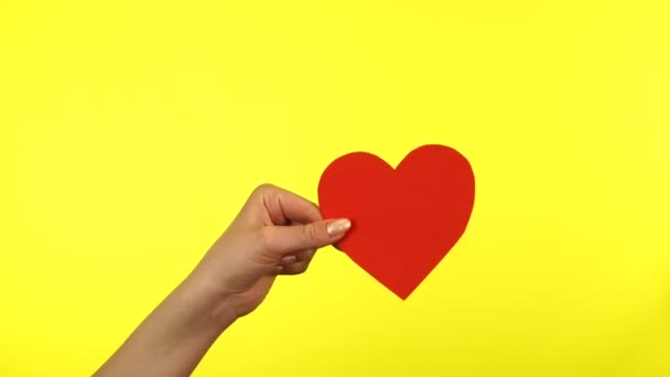 Mano masculina y femenina que mantiene unido un corazón rojo como símbolo de amor y relación — Vídeos de Stock