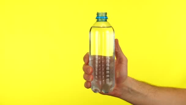 Homme main ouvre une bouteille bleue d'eau douce sur fond jaune isolé sur fond jaune — Video