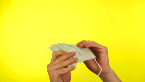 Mans hands showing surgical mask isolated on yellow. — Stock Video