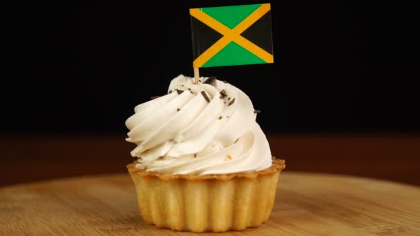 Man places decorative toothpick with flag of Jamaica into cream cake. National cuisine — Stock Video