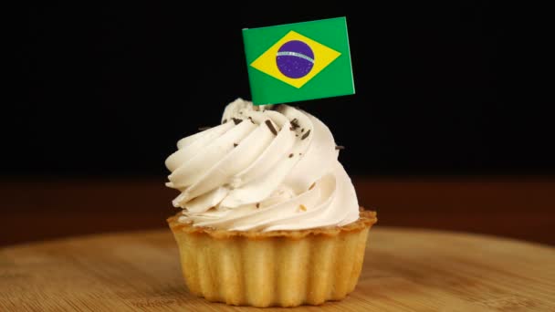 Man places decorative toothpick with flag of Brazil into cream cake. National cuisine — Stock Video