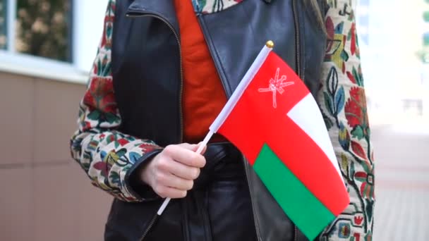 Unrecognizable woman holding Omani flag. Girl walking down street with national flag of Oman — Vídeos de Stock