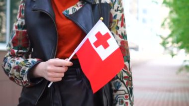 Tonga bayrağı tutan tanınmayan bir kadın. Tonga 'nın ulusal bayrağıyla sokakta yürüyen bir kız.