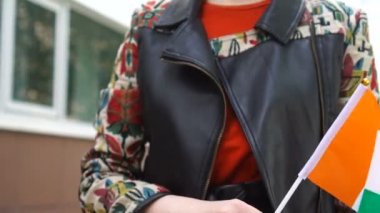 Elinde İrlanda bayrağı tutan tanınmayan bir kadın. İrlanda bayrağıyla sokakta yürüyen bir kız