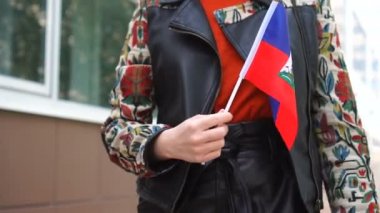 Haiti bayrağı taşıyan tanınmayan bir kadın. Haiti bayrağıyla sokakta yürüyen bir kız.