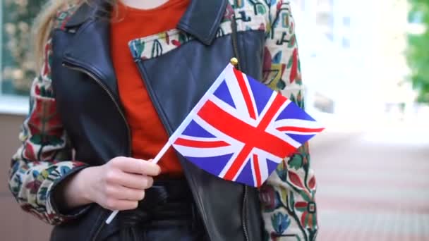 Unrecognizable woman holding Union Jack flag. Girl walking down street with national flag of United Kingdom. — Vídeo de stock