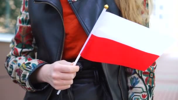 識別できない女性はポリッシュフラグを保持します。ポーランド国旗を掲げて街を歩く少女 — ストック動画