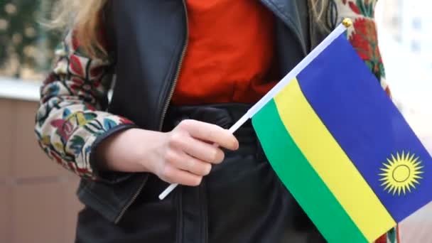 Oigenkännlig kvinna som håller Rwandans flagga. Flicka promenader ner gatan med nationell flagga Rwanda. — Stockvideo