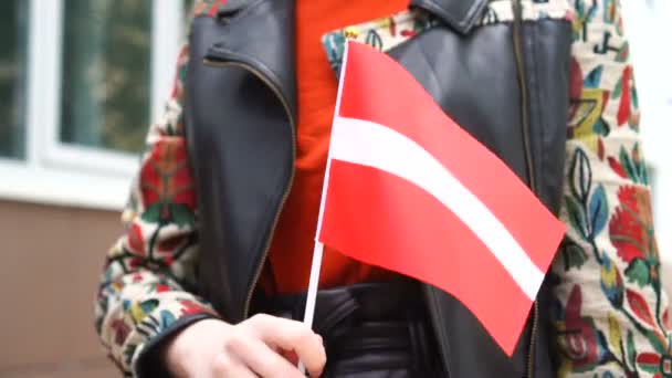 ラトビアの国旗を掲揚している。ラトビアの国旗を掲げて街を歩く少女 — ストック動画
