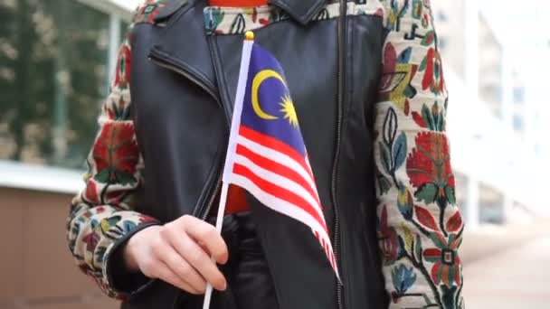 Unrecognizable woman holding Malaysian flag. Girl walking down street with national flag of Malaysia — Vídeos de Stock