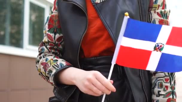Unrecognizable woman holding Dominican flag. Girl walking down street with national flag of Dominican Republic — Vídeo de stock
