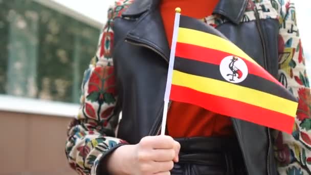 Neznámá žena držící ugandskou vlajku. Dívka kráčející po ulici s národní vlajkou Ugandy — Stock video