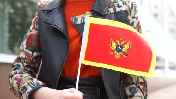 Unkenntliche Frau mit montenegrinischer Fahne. Mädchen läuft mit Nationalflagge Montenegros die Straße entlang — Stockvideo