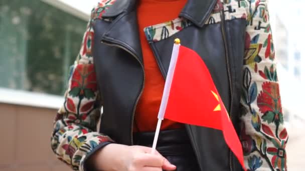 Oigenkännlig kvinna med vietnamesisk flagg. Flicka promenader ner gatan med nationell flagga Vietnam — Stockvideo