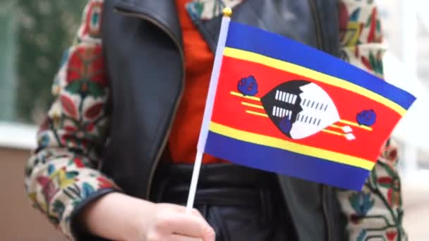 Unrecognizable woman holding Eswatini flag. Girl walking down street with national flag of Eswatini — Stock Video