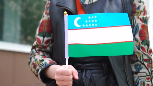 Mulher irreconhecível segurando bandeira uzbequistanesa. Menina andando rua abaixo com bandeira nacional do Uzbequistão — Vídeo de Stock