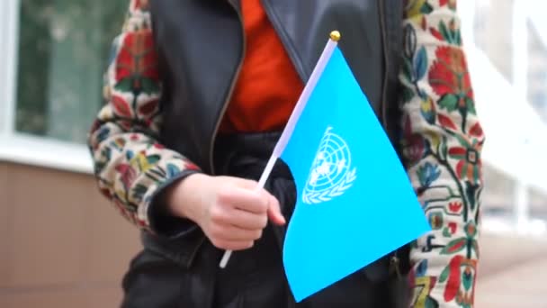 Nerozpoznatelná žena držící vlajku OSN a kráčející po ulici — Stock video