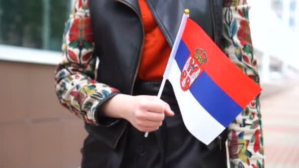 Unrecognizable woman holding Serbian flag. Girl walking down street with national flag of Serbia — Stock Video