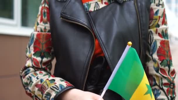 세네 갈 국기를 들고 있는 알아볼 수없는 여성. 세네갈 국기를 들고 거리를 걷고 있는 소녀 — 비디오