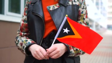 Timor bayrağı tutan tanınmayan bir kadın. Doğu Timor 'un ulusal bayrağıyla sokakta yürüyen bir kız.