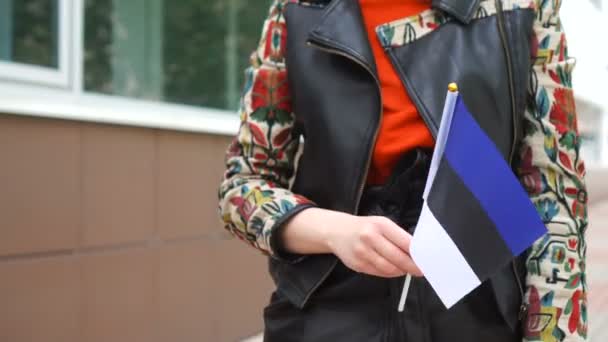 Unrecognizable woman holding Estonian flag. Girl walking down street with national flag of Estonia — Vídeo de stock