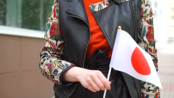 ผู้หญิงที่จําไม่ได้ถือธงญี่ปุ่น ผู้หญิงเดินลงถนนกับธงแห่งชาติของญี่ปุ่น — วีดีโอสต็อก