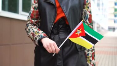 Mozambik bayrağı taşıyan tanınmayan bir kadın. Mozambik 'in ulusal bayrağıyla sokakta yürüyen bir kız.