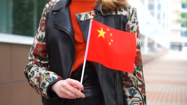 Unrecognizable woman holding Chinese flag. Girl walking down street with national flag of China — Vídeos de Stock
