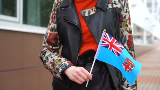 Невпізнавана жінка, що тримає фіджійський прапор. Дівчина йде по вулиці з національним прапором Фіджі. — стокове відео