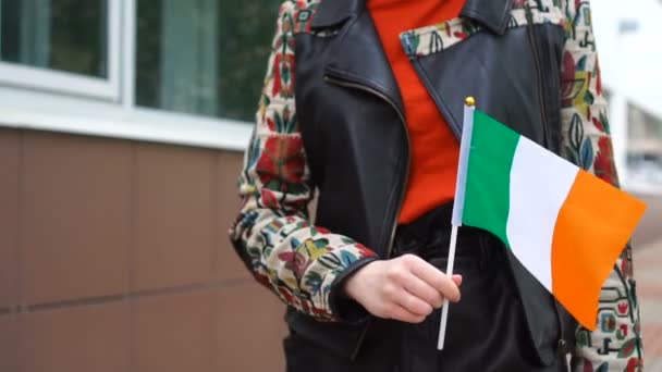 Mulher irreconhecível com bandeira irlandesa. Menina andando rua abaixo com bandeira nacional da Irlanda — Vídeo de Stock