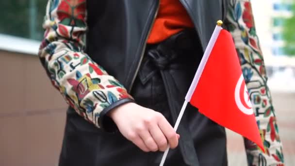 Oigenkännlig kvinna med tunisisk flagga. Flicka promenader ner gatan med nationell flagga i Tunisien — Stockvideo