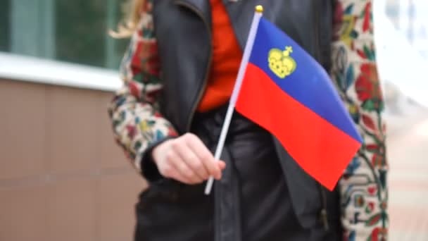 Donna irriconoscibile che tiene la bandiera dell'aviatore. Ragazza che cammina per strada con la bandiera nazionale del Liechtenstein — Video Stock