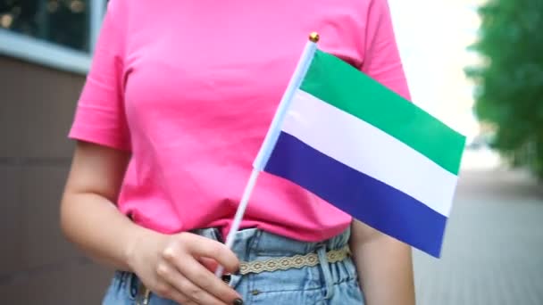 시에라 레오네의 깃발을 들고 있는 알아볼 수없는 여성. 시에라리온 국기를 들고 거리를 걷고 있는 소녀 — 비디오